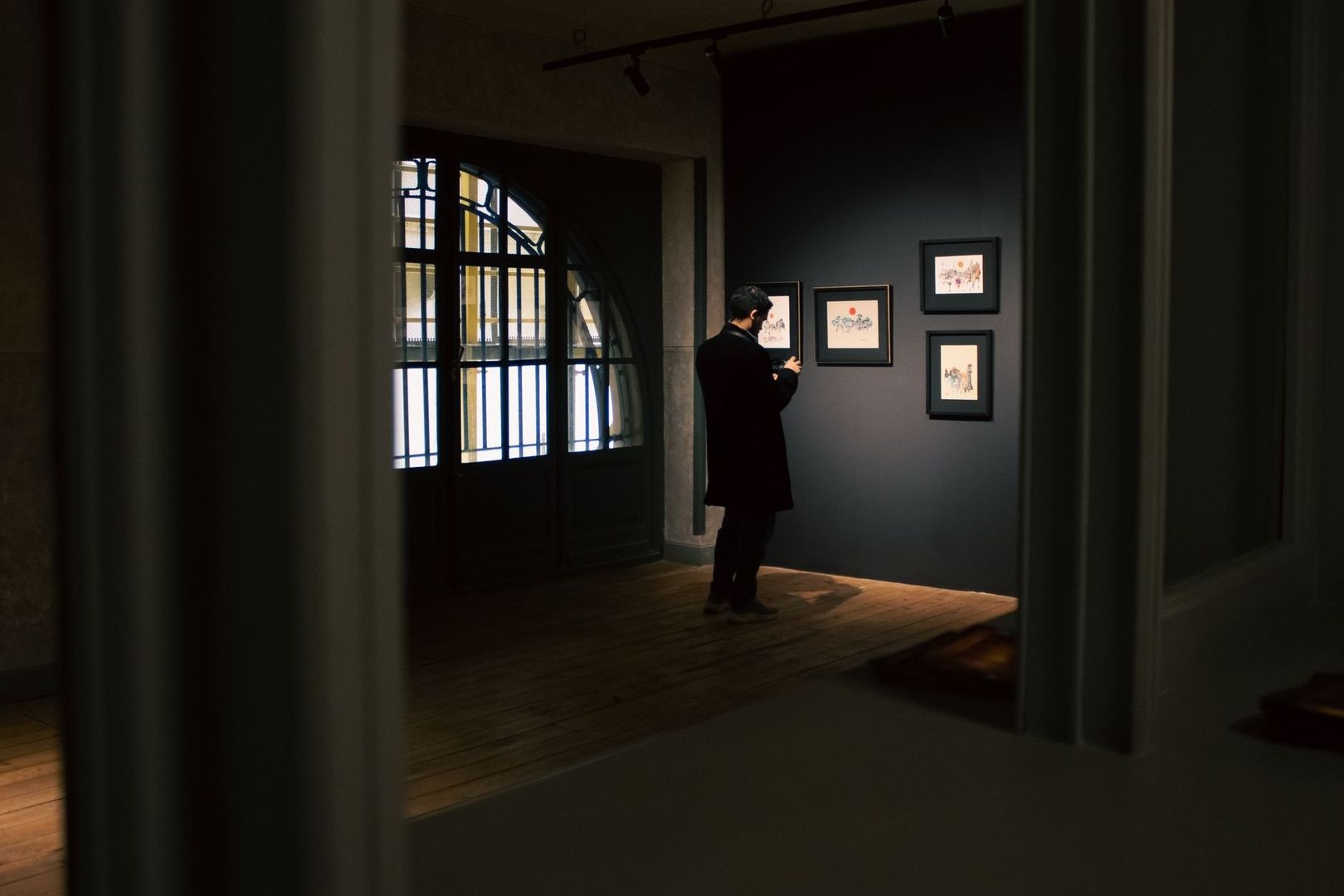 Dæmpet galleri med indrammet kunst og en besøgende under spotlys